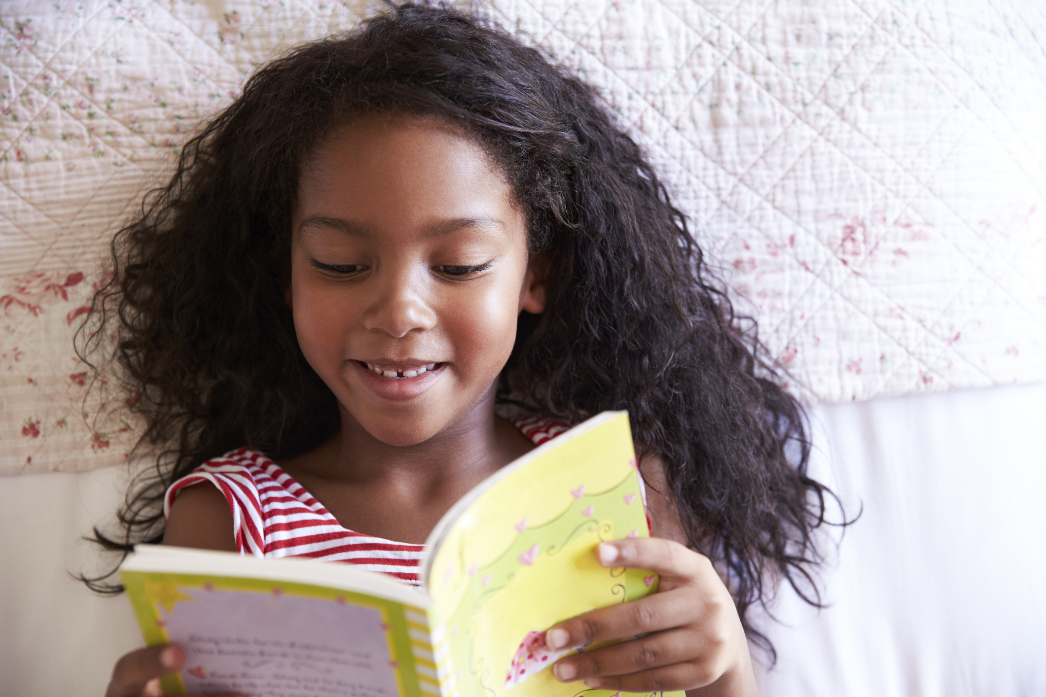 girl reading a book aloud and developing literacy skills