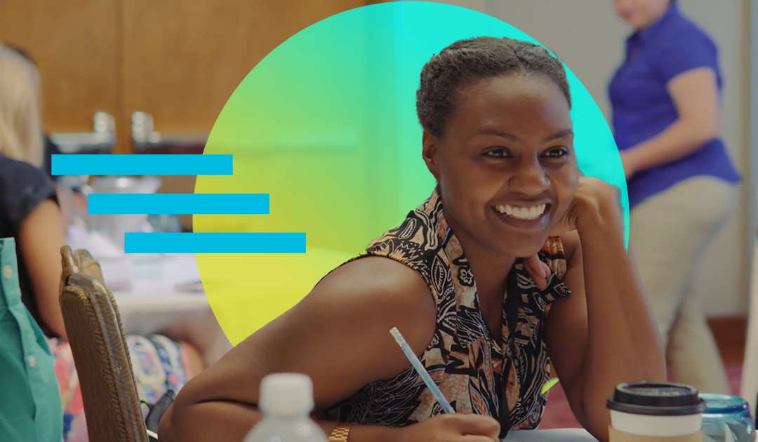 Teacher smiling at a table at a professional learning event