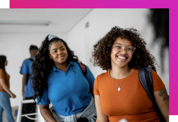 Two female students who are heritage and native speakers of Spanish standing and smiling in a Spanish for Spanish speakers class